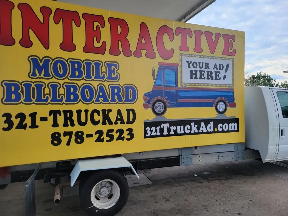 The 321 Truck Ad truck at a gas station carrying its own yellow mobile billboard banner